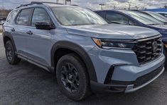 the front end of a gray 2020 honda passport parked in a lot with other cars