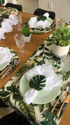 the table is set with green and white plates, silverware, and greenery