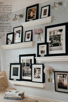 the wall is covered in pictures and framed photographs, with flowers on each shelf next to it