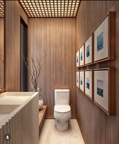 a modern bathroom with wood paneling and pictures on the wall above the toilet area