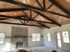 an empty living room with wood beams and stone fireplace