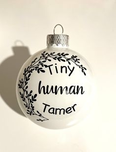 a white ornament with the words tiny human tamer on it