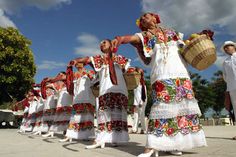 a group of women in white dresses are dancing with baskets on their heads and hands