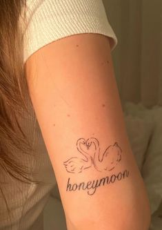 a woman with a tattoo on her arm that says honeymoon and two swans