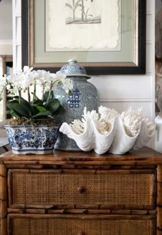 flowers are sitting on top of a dresser in front of a framed art piece and vase