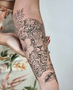 a woman with a tattoo on her arm holding onto a leopard and flower sleeve piece