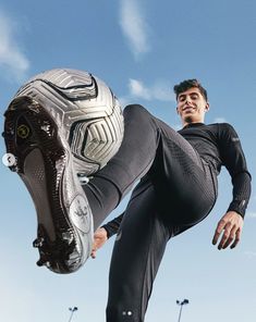 a man is jumping in the air with a soccer ball on his foot and wearing black pants