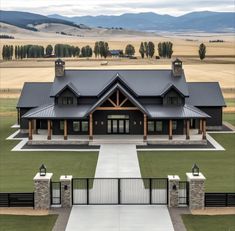 an aerial view of a large house in the middle of a field with mountains in the background