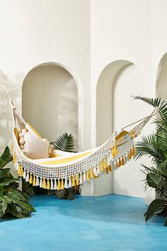 a white and yellow hammock with tassels hanging from it's sides