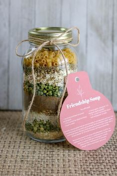 a glass jar filled with pasta and other items next to a tag that says, friendship soup