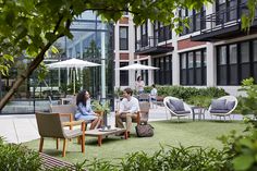 two people sitting on chairs in the middle of an open courtyard with tables and umbrellas