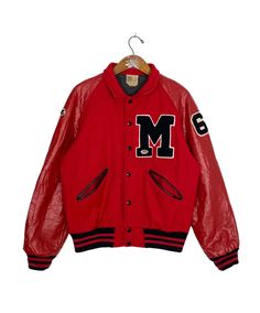 a red jacket with the letter m on it, hanging from a clothes hanger