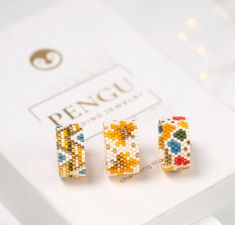 three pairs of beaded earrings sitting on top of a white box next to each other