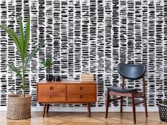 two chairs and a table in front of a wall with black and white designs on it