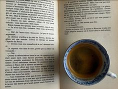 a cup of coffee sitting on top of an open book