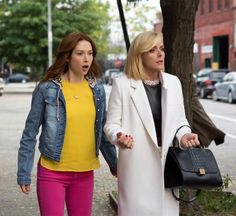 two women walking down the street with one holding her hand out to another woman's shoulder