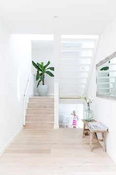 there is a plant in the vase on the table next to the stairs that lead up to the second floor