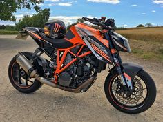 an orange and black motorcycle parked in the dirt