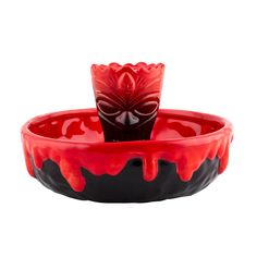 a red and black bowl with a flower in it on a white background, the bowl is filled with water