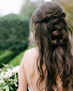 the back of a woman's head, with flowers in her hair and white dress