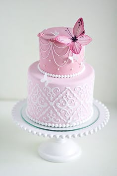 a pink and white cake with a butterfly decoration on the top, sitting on a plate