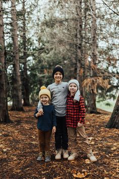 three children are standing in the woods with their arms around each other and smiling at the camera