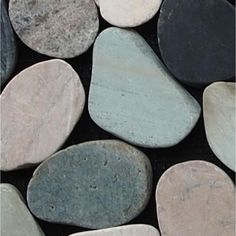 several different colored rocks sitting on top of each other in a black surface with white and gray ones