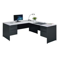 an office desk with a computer on top of it and a plant in the corner