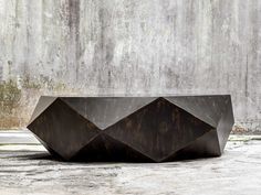 a large metal sculpture sitting on top of a cement floor next to a concrete wall