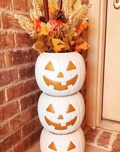 three pumpkins are stacked on top of each other in front of a brick wall