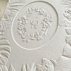 an intricately carved white paper with flowers and leaves on the edges is shown in this close up photo