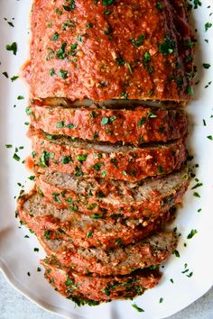 sliced meatloaf on a white plate with parsley sprinkled on top