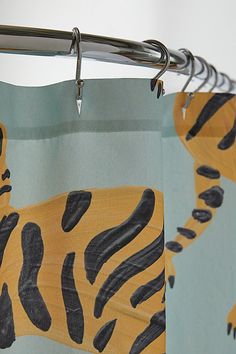 a shower curtain with a tiger print on it's side hanging from a metal rod