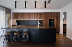 an open kitchen with bar stools next to the counter top and wooden cabinetry