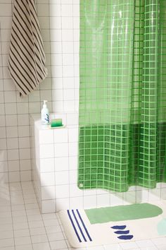 a green shower curtain in a white tiled bathroom