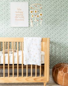 a baby's crib in front of a green wall with flowers on it