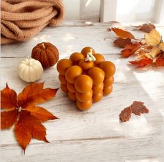 a bunch of grapes sitting on top of a wooden table next to leaves and pumpkins