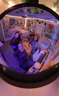 three people taking a selfie in a mirror with christmas decorations on the wall behind them