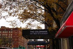 a street sign for the colondade in front of some tall buildings and trees