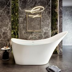 a bathroom with marble walls and flooring, a white bathtub in the center