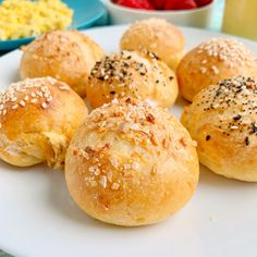 rolls with sesame seeds and other toppings on a white plate next to strawberries