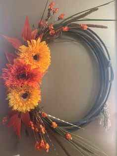 an orange and yellow wreath is hanging on the wall next to a blue rope with flowers