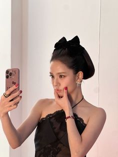 a woman taking a selfie in front of a mirror wearing a black dress and holding a cell phone up to her face