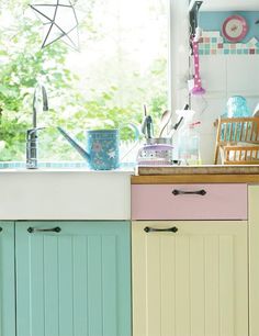 a kitchen with colorful cabinets and an open window