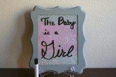 a sign that says the baby is a girl in black and pink glitter on it