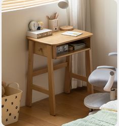 a small wooden desk with a lamp on top of it next to a chair and window