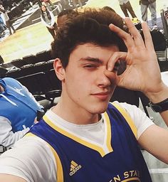 a young man holding his hand up in the air at a basketball game while wearing a blue and yellow uniform