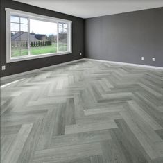 an empty room with gray walls and wood flooring