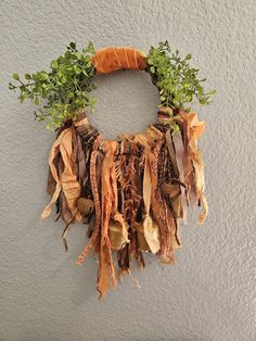 a wreath made out of leaves and branches hanging on the wall with no one around it