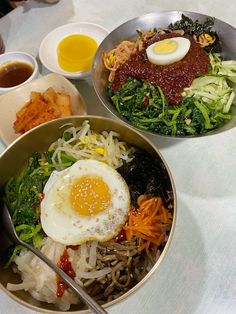 two bowls filled with different types of food on top of a white tablecloth covered table